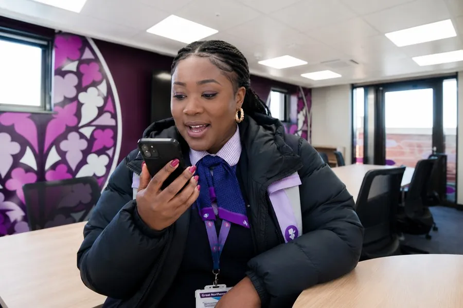 A frontline rail employee speaking naturally into her phone while using RAISE