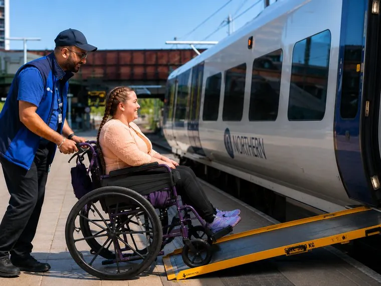 A member of staff speaking with a wheelchair user on a platform